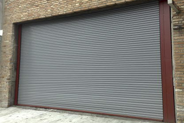 Porta de aço cinza em fachada de tijolo